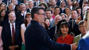 Andy Burnham, wearing glasses and a dark suit, engaging with a diverse group of professionals at a formal event.