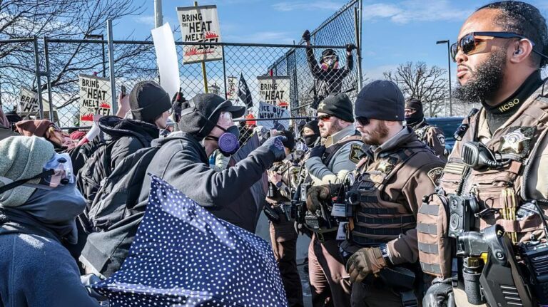 Law enforcement officers stand guard as protestors demonstrate against ICE operations in Minneapolis